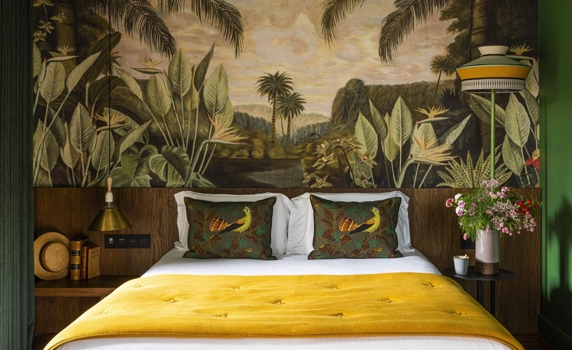 Room decorated with yellow and green details and hand painted wallpaper of palmtrees and leaves hotel boutique Les Étangs de Corot.   